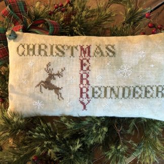 Photo of finished pillow tuck from Christmas Merry Reindeer by Falling Star Primitives, displayed on top of evergreen branches